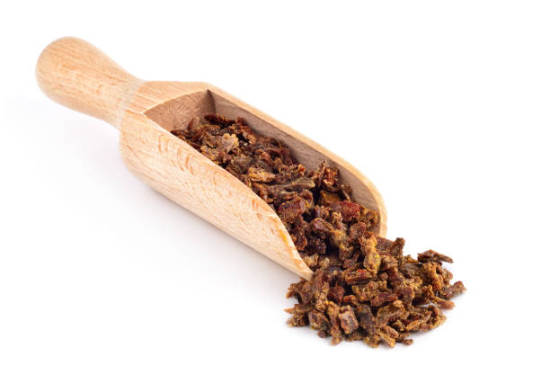 Beet propolis granules in a wooden spoon are isolated on a white background. Natural antibiotic. Beekeeping product. Apitherapy